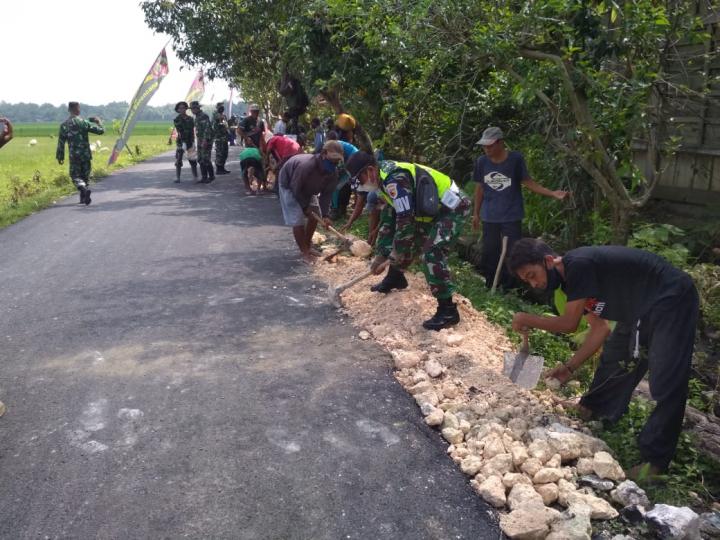Anggota Satgas TMMD Bojonegoro Gotong Royong Bareng Warga Timbun Tepi Aspal